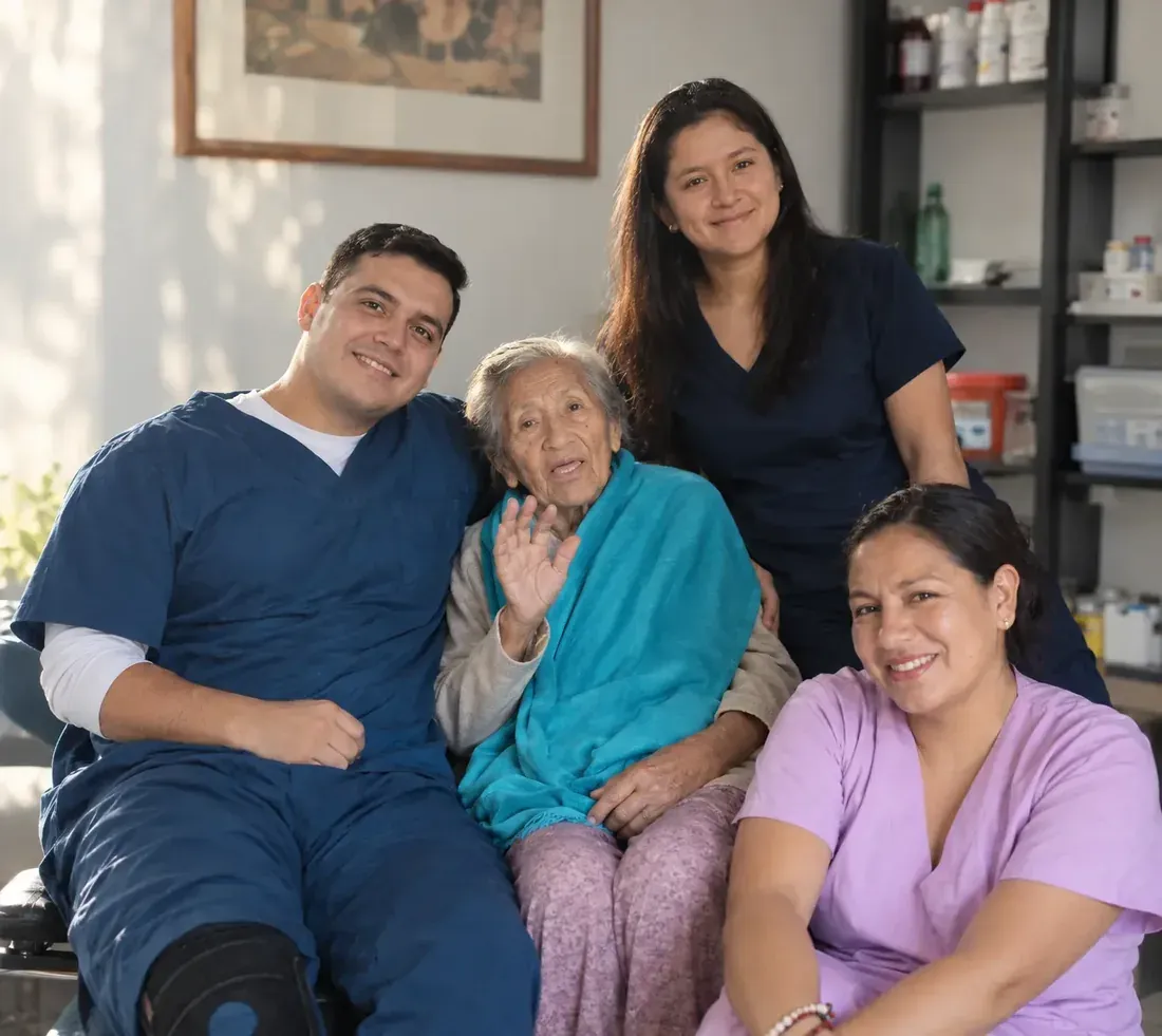 Tres integrantes del equipo junto a una residente que saluda a la cámara